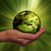 das Bild zeigt eine grüne Weltkugel in einer geöffneten Hand und symbolisiert so das System Nachhaltigkeit